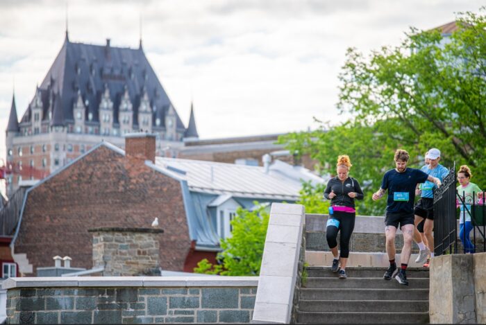 PHOTO des COUREURS en descendant les escaliers et le château Frontenac en arrière-plan